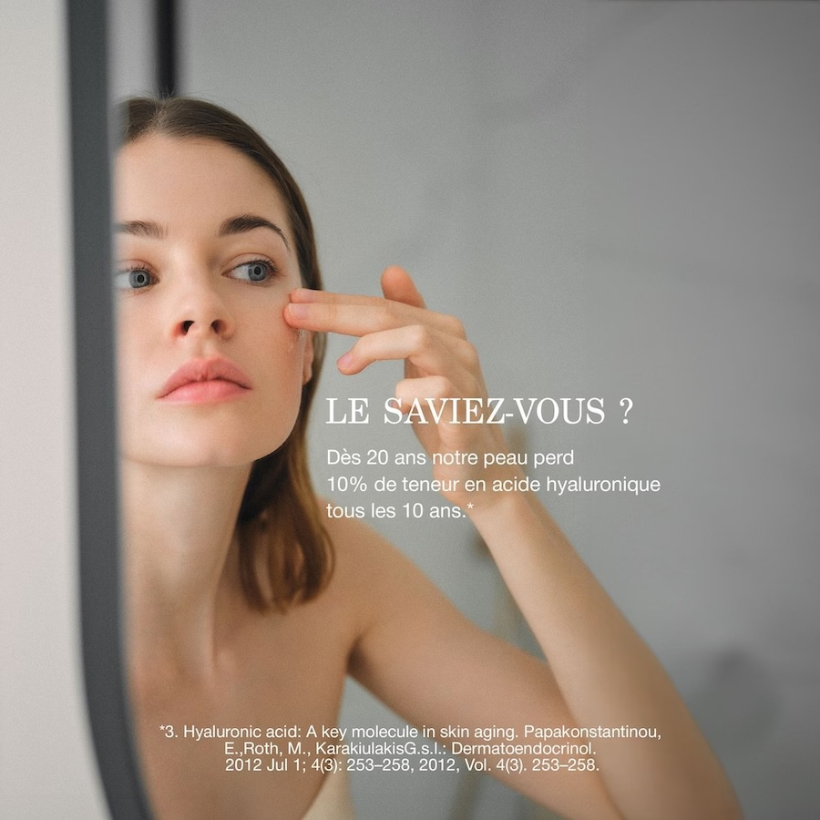 Femme appliquant un soin sur sa joue, avec une information sur l’acide hyaluronique dans la peau.